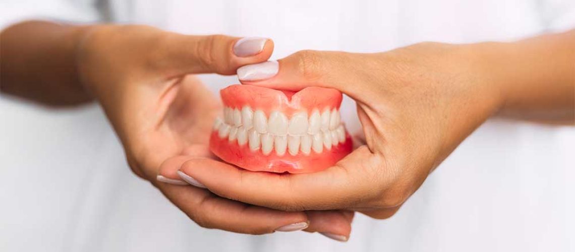 denture-dentist-holding-dentures